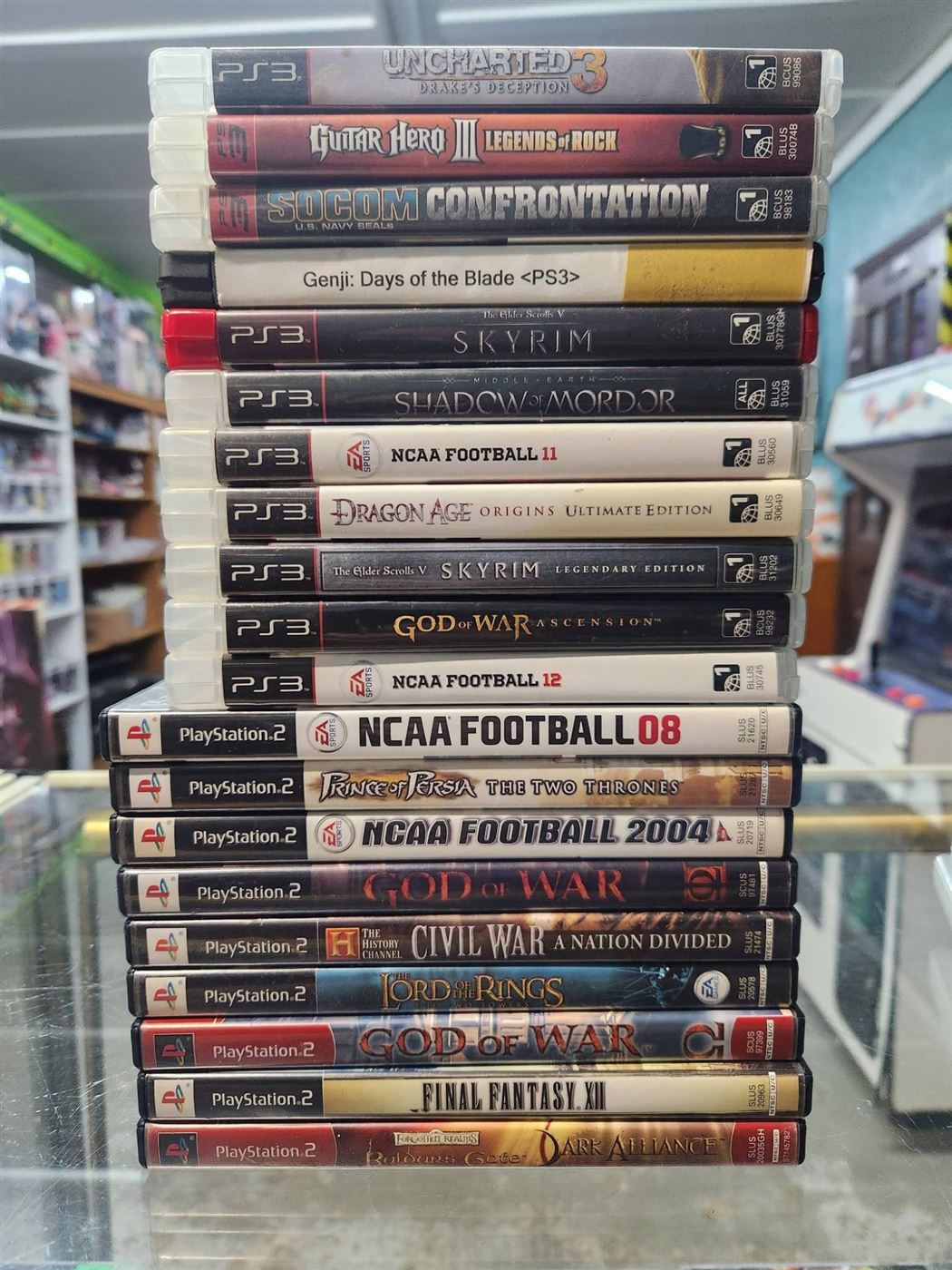 Stack of PS3 and PS2 games including Uncharted 3, Skyrim and God of War